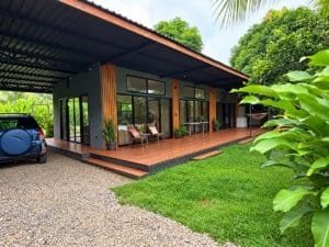 Modern tropical home with large glass windows and pool near the beach.