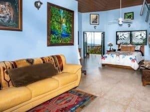 Interior of ocean view estate with bedroom, tropical decor, and balcony view.