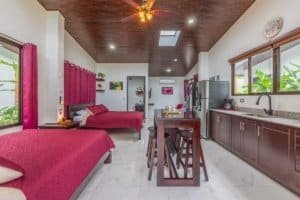 Spacious 3-bedroom villa with red bedding, open kitchen, and pool near Dominical.