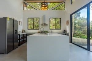 Modern kitchen with island, stainless appliances, and large windows in Costa Rica home.