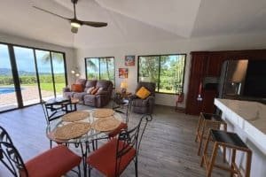 Bright living area with large windows and ocean view, dining table, and seating.