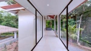 Glass-walled corridor with outdoor greenery and pool area view.