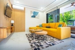 Bright living room with yellow sofa, modern decor and glass doors to lush greenery.