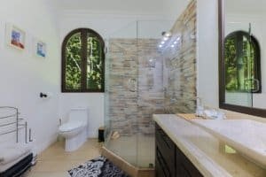 Modern bathroom with glass shower, mountain view, and elegant decor.