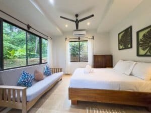 Spacious bedroom with ocean view, modern decor, and garden nearby in Dominical.