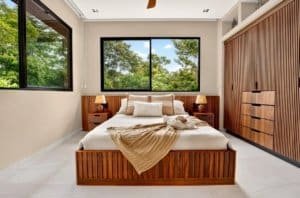 Dominical real estate luxury bedroom with wooden bed and large windows.