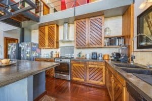 Panoramic kitchen with wooden cabinets, stainless steel appliances and dark countertops.