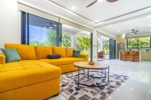 Bright orange sectional sofa in a sunny open living area with large glass doors.