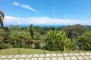 Beautiful tropical garden with ocean view, lush greenery, and blue sky in Dominical.