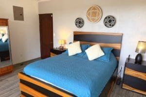 Bedroom with blue bedspread, modern wooden furniture and coastal decor in a bright, airy suite.