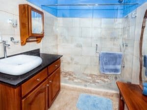 Bathroom with walk-in shower, wooden vanity, and blue towels in Dominical.