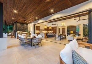 Open-concept living area with wood ceiling, stylish seating, and large glass doors.