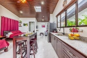 Open-concept kitchen and dining area with red accents and large windows.