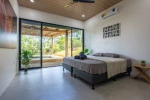 Dominical real estate bedroom with king bed, large glass doors to outdoor patio and jacuzzi area.