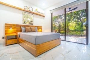 Condo bedroom with wood bed, large glass door to garden, modern bedding.