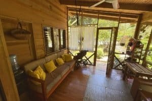 Interior of a jungle hotel in Dominical with wooden decor, sofa, and outdoor view.