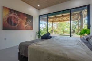 Bedroom with large sliding glass doors opening to a covered patio and greenery.