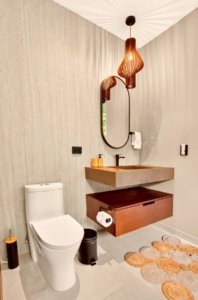 Modern bathroom with wall-mounted sink, wooden vanity, and contemporary pendant lighting.