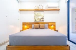 Condo-style bedroom with king bed, modern wooden headboard and nightstands.