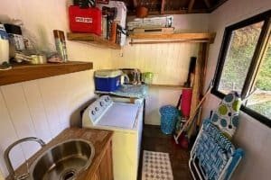 Laundry area with washing machine, sink, and storage in jungle home.