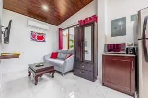 Interior living area with sofa, coffee table, kitchenette and glass door in Dominical.
