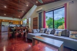 Turn-key coastal home living room with large windows and wooden ceiling in Dominical.