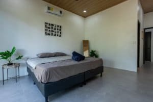 Creekside bedroom with large bed, nightstands, and tropical plants.