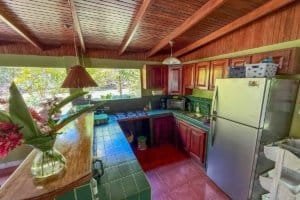 Interior view of a jungle hotel kitchen with wooden ceiling and green tiles.