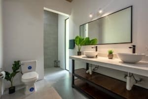 Creekside bathroom with double vessel sinks, large mirror, and modern fixtures in a luxury Costa Ric.