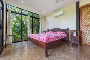 Cozy bedroom with large glass doors opening to lush tropical greenery.