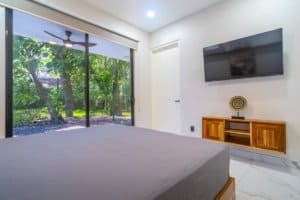Ocean view condo bedroom with large glass doors to tropical garden in Dominical Costa Rica.