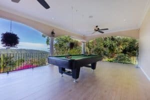 Covered patio with pool table, overlooking lush landscape and mountains.