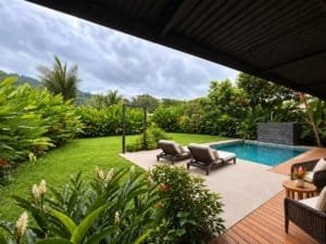 Beautiful tropical home with pool, lounge chairs, and lush garden near the beach.