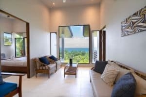 Bright living room with ocean view, tropical greenery, and modern decor.