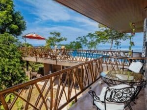 Balcony with ocean view, tropical trees, and outdoor furniture in Dominical.