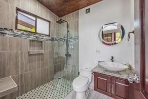 Modern bathroom with glass shower, circular mirror, and granite vanity.