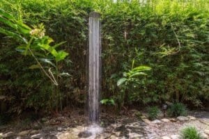 Turn-key coastal home garden with water fountain and lush greenery.