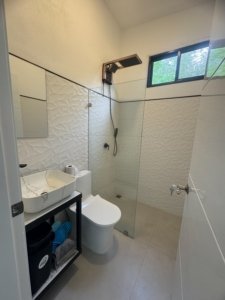 Modern walk-in shower and vanity in a compact, bright bathroom with glass partition.