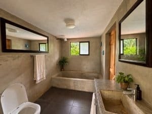 Interior of a tropical home with a bathtub, sink, and large mirrors.