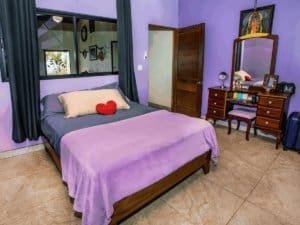 Bedroom with purple walls, bed, dresser, and tropical decor in Costa Rica.