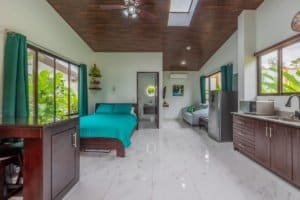 Open-concept living area with two bedrooms, kitchen, and pool view in Dominical real estate.