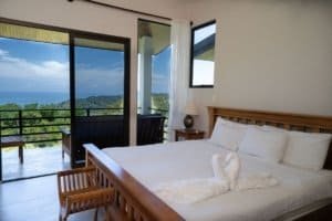 Bedroom with ocean view, balcony, and tropical landscape in Dominical.