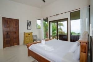 Spacious bedroom with ocean view, balcony, and tropical surroundings in Dominical.