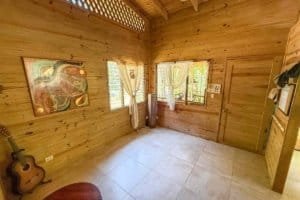 Interior of a wooden jungle hotel room with windows, curtains, and guitar in Dominical.