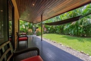 Covered porch with seating and lush tropical garden in Dominical Real Estate scene.