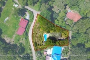 Aerial view of a fenced property with pool, greenery, and surrounding houses.