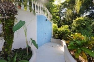 Outdoor shower in lush tropical garden with greenery and trees.
