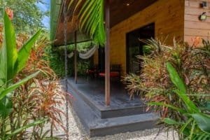 Turn-key 2-bedroom coastal home with a shaded porch in Costa Rica, tropical plants surrounding the入口.