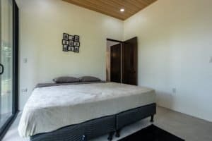 Bright bedroom with large window, queen bed, and minimalist decor in a Costa Rica home.