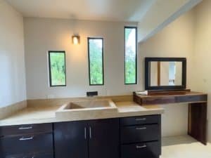 Contemporary bathroom with vanity, mirror, and natural light from windows.